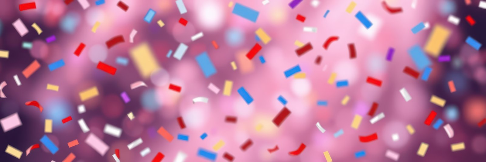 Colorful confetti falls against a pink, blurred background, creating a festive and celebratory mood